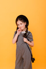Obraz premium Portrait of baby girl holding photo camera isolated on yellow background