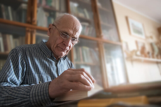 Personality authentic portrait of bald senior man sitting at table and reading book