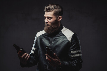 Bearded guy posing with bottles in dark background