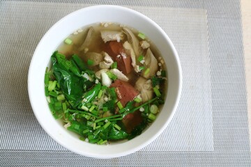Boiled pork blood with gourd leaves or blood tofu soup in white bowl. Food and object concept.