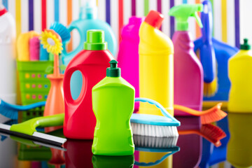 Spring house and office cleaning theme. Colorful set of bottles with clining liquids and colorful cleaning kit on background in the form of colorful stripes.
