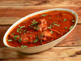 Chicken korma made of indian spices served in a bowl over a wooden rustic background. selective focus