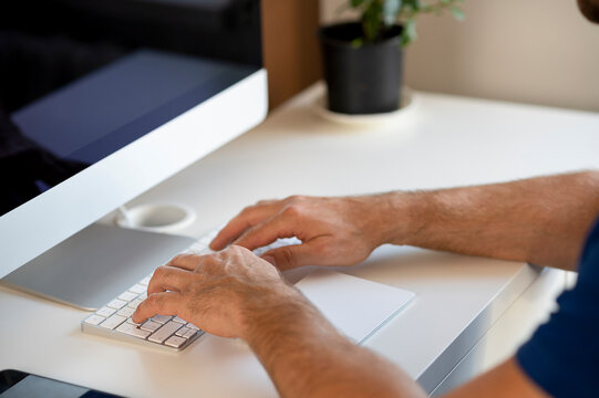 Side view of businessman hands using computer while sitting at desk in home office