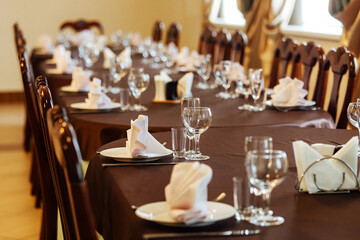 a set table in the restaurant. the cafe hall is waiting for guests for the holiday. clean tablecloth and dishes without food