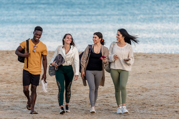 Cheerful diverse friends walking on beach together