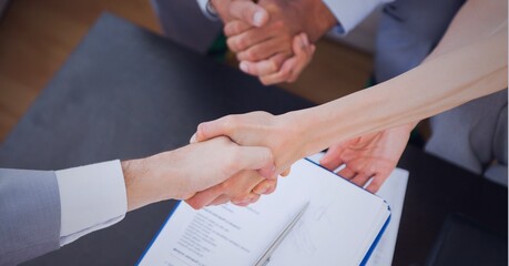 Businesswomen shaking hands over desk in office