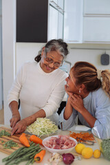 Filipino family cooking together at home - Granddaughter helping her grandmother to cook a traditional asian meal - Senior woman teaching a recipe to her granddaughters - 422830548