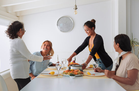Family of four filipino women sharing lunch together at home - Family spending quality time cooking asian food and eating it together