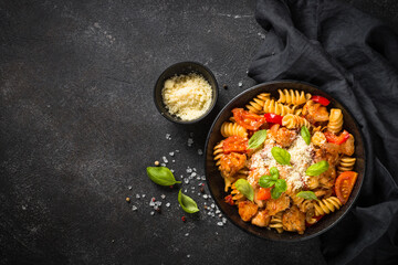 Pasta chicken with vegetables on black.
