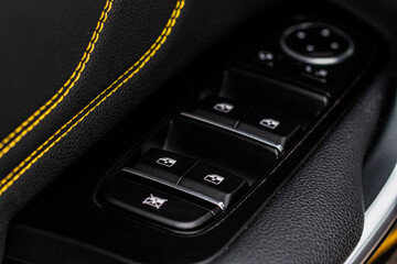 Obraz premium Close up view of button controlling window in modern car interior. Vehicle interior detail. Door handle with windows controls