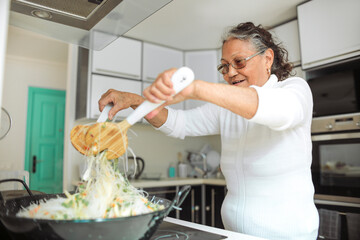Senior filipino woman cooking a traditional asian meal at home