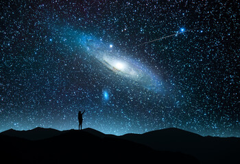 The girl silhouett stands on the hill and looking at the bright starry sky  with Andromeda galaxy...