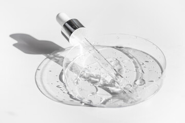 Transparent liquid gel or hyaluronic serum acid in petri medical dish with pipette. Hydrating and skin care concept