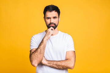 Serious man with hands folded standing isolated on yellow background and looking at camera