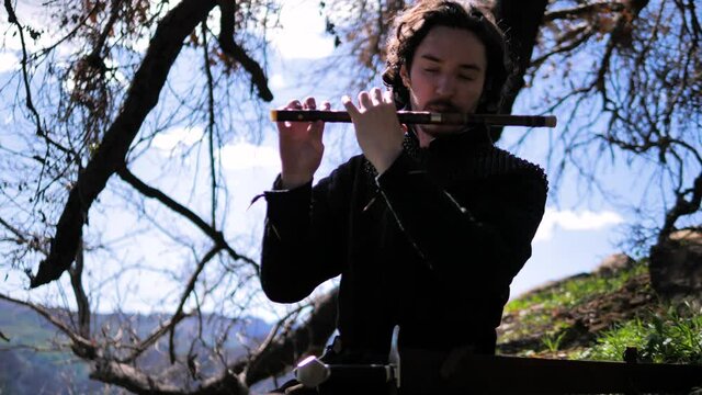 Man in medieval outfit plays the flute.  4k, tracking shot, 60fps