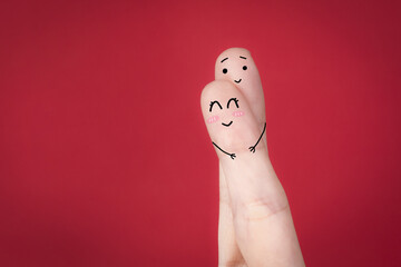 Closeup of a funny loving couple doodle on fingers against a red background