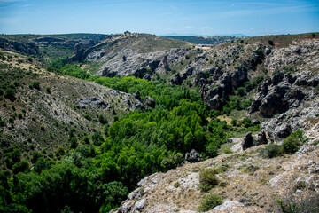 Fototapeta na wymiar Pequeño valle o garganta de un río con árboles de ribera en la parte baja y rocas en la parte alta en el término municipal de Pelegrina, España