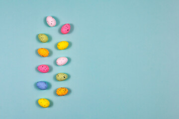 Obraz premium Easter colorful eggs in the form of two tracks on a blue background. Top view, copy space. Place for an inscription.