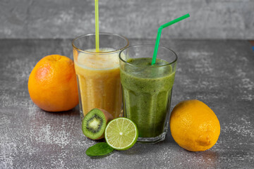 Two tall glasses of orange juice and a banana-orange kiwi and spinach smoothie