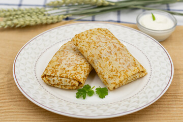 Pancakes rolled up in an envelope on a plate. Served with sour cream on a napkin.