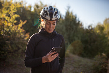 Smiling female cyclist using her smartphone