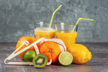 An orange wrapped with a measuring tape and a caliper surrounded by fresh fruits