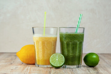 Tall glass with kiwi and spinach smoothie surrounded by fruits on a wooden table