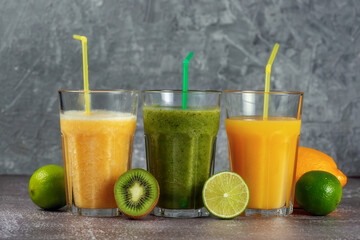 Three glasses in a row with orange juice and banana orange kiwi smoothie