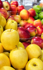 Yellow, red, green apples are sold in the market, blurred background, vertical image.