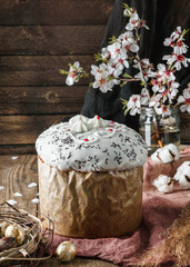 Obraz na płótnie Canvas Glazed Easter cake or bread kulich on rustic wooden table with golden easter eggs and spring flowers. Happy Easter holiday