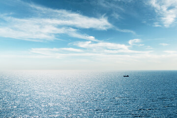 Lonely fishing ship trawler boat on ocean water. Calm clear sea sunny weather. Beautiful horizon of seascape