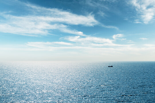 Lonely fishing ship trawler boat on ocean water. Calm clear sea sunny weather. Beautiful horizon of seascape - Powered by Adobe