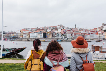 back view of three women sightseeing Porto views by the river. Travel and friendship concept