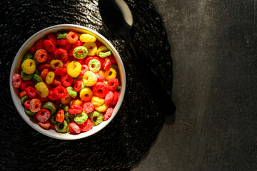 Detail of sunlight reaching bowl with fruit rings with milk served for breakfast. Capture top view.