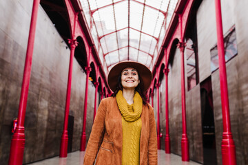 young caucasian woman outdoors over red columns building. Travel concept