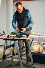 a man working with equipment on a wooden table in his backyard