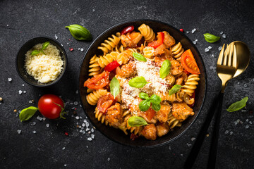 Pasta chicken with vegetables on black.