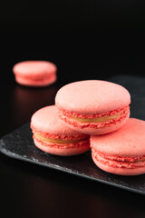 pink macaroons on a tray on a black background