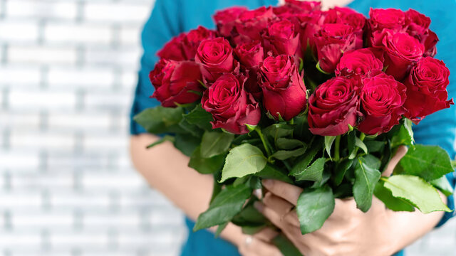 The girl holds in her hands a gorgeous bouquet of red roses on a white background. Banner for advertising flower delivery with copy space. Gift on a date for Valentine's Day, Birthday. - Powered by Adobe