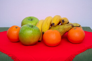 red and green tablecloth with pears, bananas, oranges and fresh green apples 
