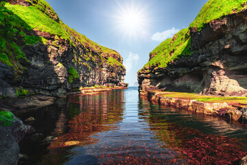 Fototapeta na wymiar Beautiful view of dock or harbor with clear water and red seaweed in Gjogv village, Eysuroy island, Faroe Islands, Denmark. Landscape photography