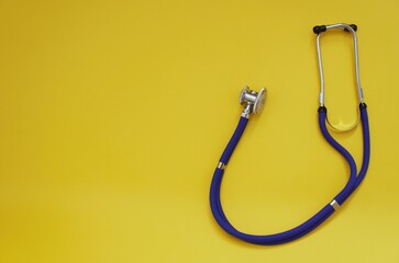 blue stethoscope lies on a yellow background. a phonendoscope on a bright yellow background can be...