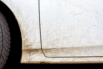 white dirty car in the splash of the slurry the driver door and the front fender of the vehicle closeup, nobody.