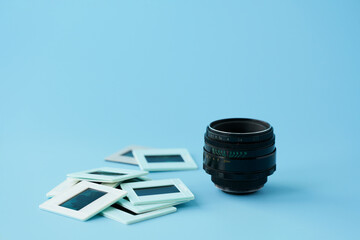 Retro photo lens next to transparencies on a blue background. Selective focus. Copy space.