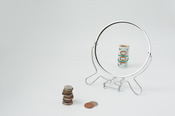 Coins in front of the mirror are reflected as bills