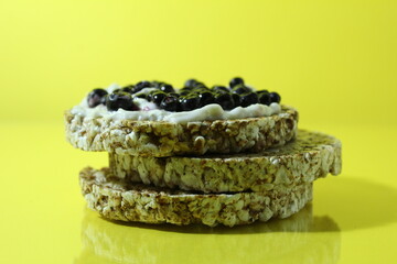 Healthy breakfast snack breads with melted cheese and blueberry berries lie a stack of balance food on a yellow background with room for text