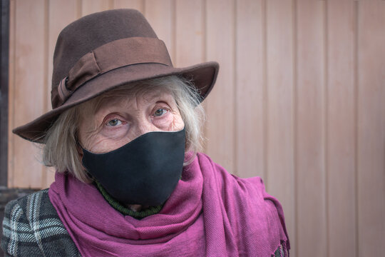 Happy Older Woman In A Black Protective Mask Against Coronavirus Infection. COVID-2019 Quarantine. Senior Health. Threat To The Life Of The Elderly Coronavirus. Fashionable Grandmother In A Hat