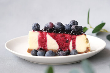 Cheesecake with blueberry syrup and fresh berries on plate. Sweet delicious homemade cake.