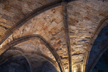 Arched arches of the castle. Antique stone ceiling with lighting. Interesting grunge background.