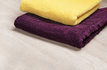 Towels in contrasting colors on a light background. Yellow and purple bath towels 